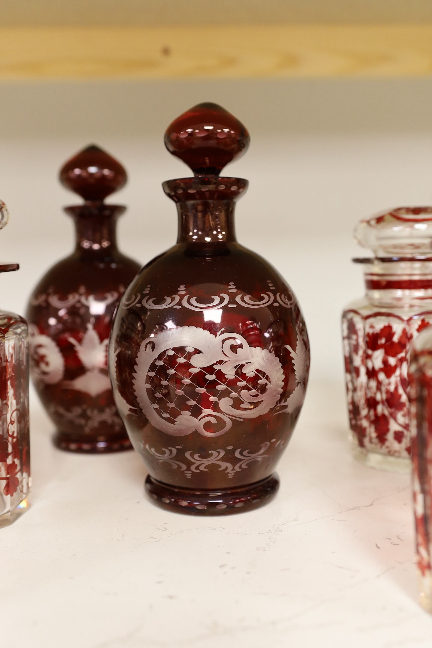 A pair of 19th century wheel engraved ruby glass decanters with stoppers, and seven ruby stained glass jars, tallest 21cm (9)